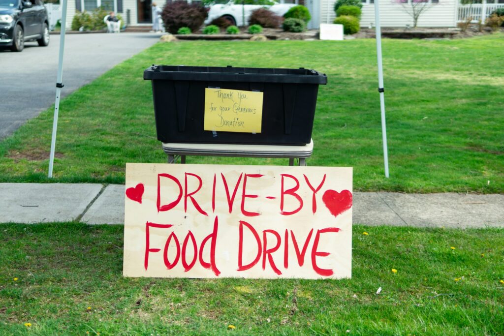 Bin for food donations on a curb with a sign on it saying "Drive-by Food Drive"