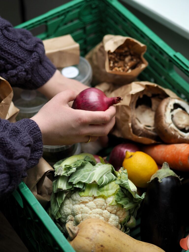 Person going through a bin of vegetables