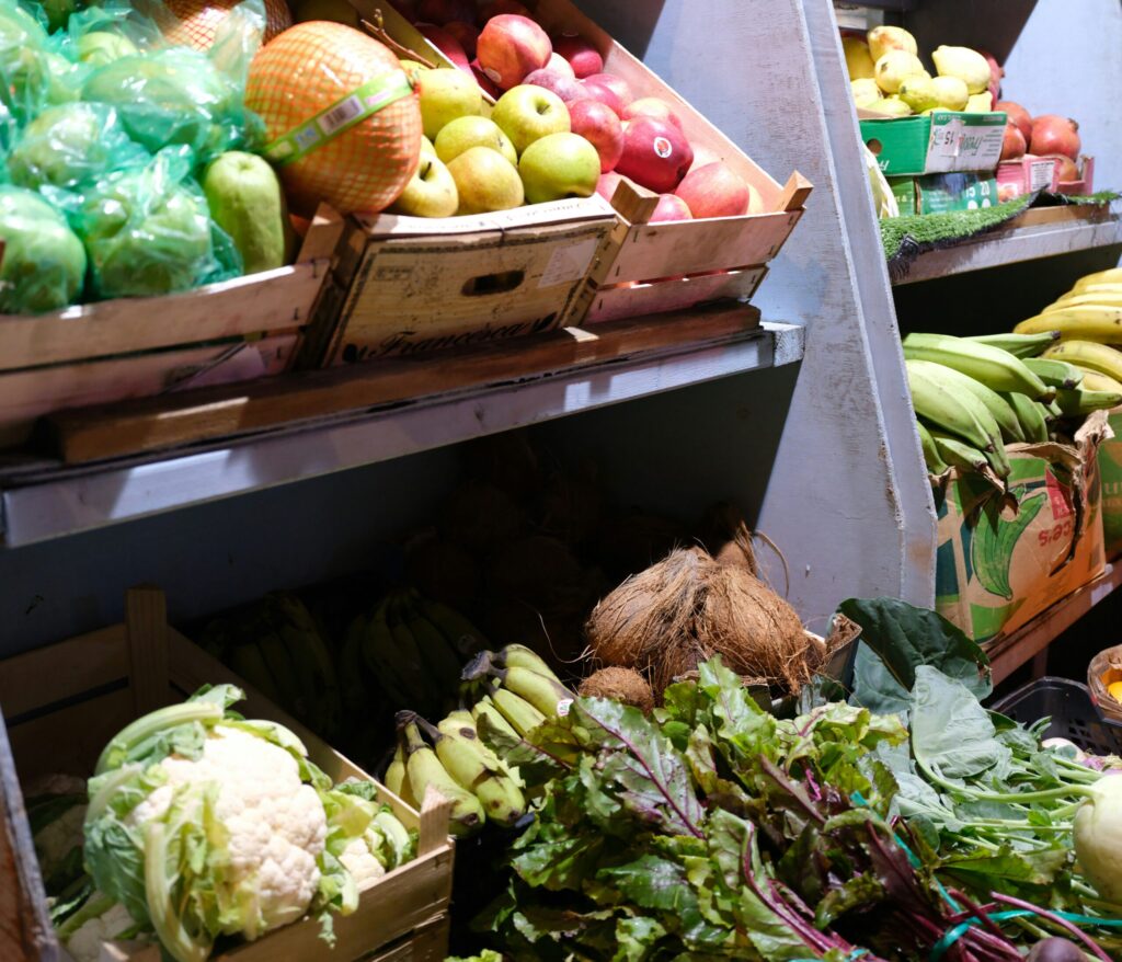 Shelves of fruit and vegetables like cauliflower, corn on the cob and apples
